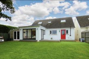 a white house with a red door and a yard at Beautiful 4-Bed House with countryside views in Haverfordwest