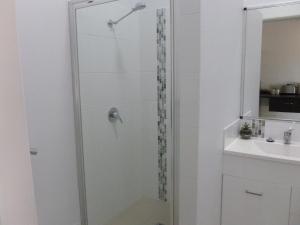 a bathroom with a shower, sink, and mirror at Capricorn Hotel in Blackwater