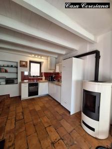 a large kitchen with white cabinets and a fireplace at Antica torre del castello Casa Ceresiana in Carabietta