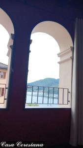 two arched windows in a building with a view of the water at Antica torre del castello Casa Ceresiana in Carabietta