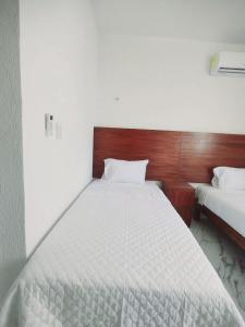 a bedroom with a white bed with a wooden headboard at Departamento en tulum Quintana roo in Tulum