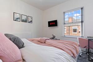 a bedroom with a bed with a clock on the wall at Masterson House By RMR Accommodations - NEW - Sleeps 9 - Modern - Parking - Central in Stoke on Trent