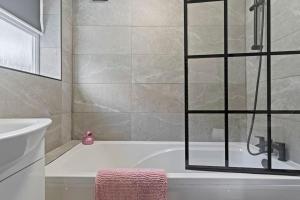 a bathroom with a bath tub with a glass shower door at Masterson House By RMR Accommodations - NEW - Sleeps 9 - Modern - Parking - Central in Stoke on Trent