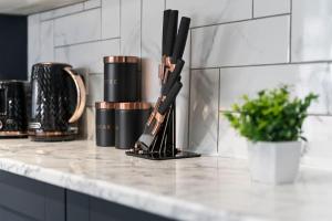 a kitchen counter with two knives and a cup at Masterson House By RMR Accommodations - NEW - Sleeps 9 - Modern - Parking - Central in Stoke on Trent