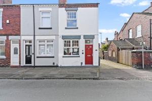 a white house with a red door on a street at Masterson House By RMR Accommodations - NEW - Sleeps 9 - Modern - Parking - Central in Stoke on Trent