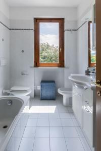 a white bathroom with two sinks and a window at Villa vicino al mare con giardino e parcheggio in Cinquale +21 photos