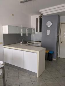 a kitchen with white cabinets and a clock on the wall at Appartamento a Riccione con balconcino vista mare in Riccione