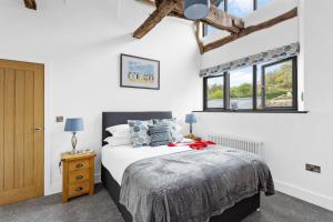 a bedroom with a bed and two windows at The Granary, Higher Yalberton Farm in Paignton