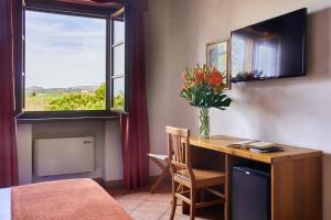a room with a desk with a vase of flowers on it at Hotel Fattoria Belvedere in Guardistallo