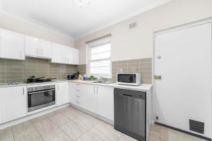 a kitchen with white cabinets and a microwave at Harbour Bridge View 2BR Resort in Sydney