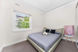 a white bedroom with a bed and a window at Harbour Bridge View 2BR Resort in Sydney