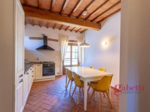 a kitchen with a white table and yellow chairs at La Loggia - I Borghi Della Selvaccia in Cennina