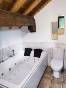 a white bathroom with a toilet and a bath tub at Alojamiento entero G&G con piscina in Bareyo