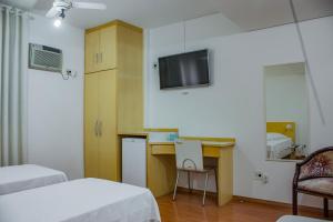 a room with two beds and a desk and a tv at Hotel San Gabriel in Sao Paulo