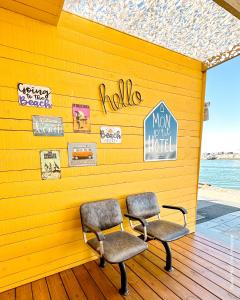 two chairs against a yellow wall with signs on it at Mon P'tit Hôtel in Le Grau-dʼAgde