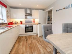 a kitchen with white cabinets and a wooden floor at Beachside in Prestatyn