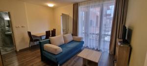 ein Wohnzimmer mit einem blauen Sofa und einem Fenster in der Unterkunft APART SUN Travel SUNNY BEACH in Sonnenstrand