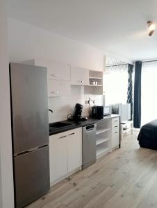 a kitchen with white cabinets and a stainless steel refrigerator at Apartament Diament 1 - Jezioro Nyskie in Nysa