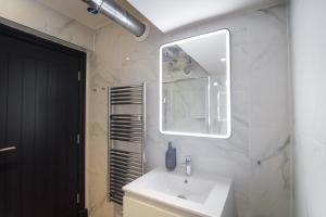 a bathroom with a white sink and a mirror at Omnia by The Heim Residences in Manchester