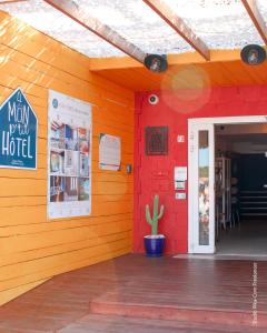 a building with a red wall with a door and a cactus at Mon P'tit Hôtel in Le Grau-dʼAgde