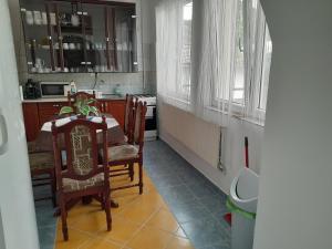 a kitchen with a table and chairs and windows at Varázsfa Vendégház in Demjén