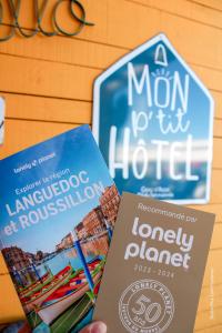 une personne tenant deux livres à côté d'un panneau dans l'établissement Mon P'tit Hôtel, au Grau-dʼAgde