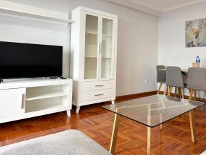 een woonkamer met een televisie en een tafel en stoelen bij Piso en el centro de Vigo 2 dormitorios Brasil in Vigo