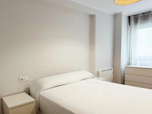 een witte slaapkamer met 2 bedden en een raam bij Piso en el centro de Vigo 2 dormitorios Brasil in Vigo