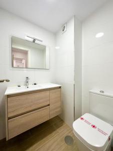 een badkamer met een toilet, een wastafel en een spiegel bij Piso en el centro de Vigo 2 dormitorios Brasil in Vigo