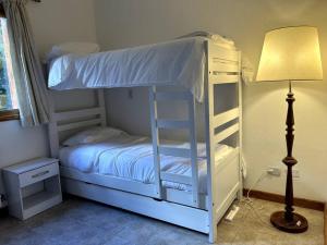 Litera blanca en habitación con lámpara en Casa en Bosque de Pinos en San Carlos de Bariloche