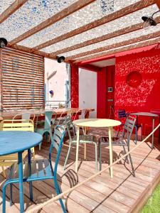 a patio with tables and chairs and a red wall at Mon P'tit Hôtel in Le Grau-dʼAgde