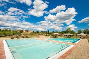 a large swimming pool with a blue sky with clouds at La Siepe - I Borghi Della Selvaccia in Cennina