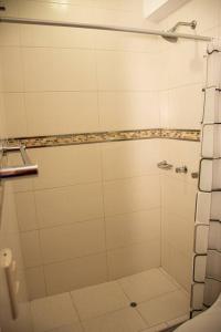 a bathroom with a shower with white tiles at Departamento Familiar Alado del aeropuerto in Cusco