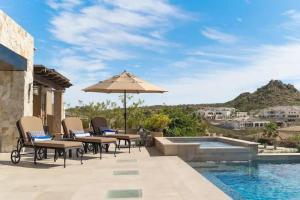 a patio with chairs and an umbrella next to a pool at Phenomenal Oceanview Villa in Puerto Los Cabos in San José del Cabo