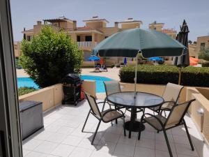a table and chairs with an umbrella on a patio at Cyprus-2 bedrooms both ensuite pool patios wifi in Polis Chrysochous