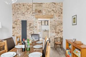 a dining room with a table and chairs and a stone wall at The Linhay, Higher Yalberton Farm in Paignton