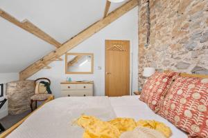 a bedroom with a bed and a stone wall at The Linhay, Higher Yalberton Farm in Paignton