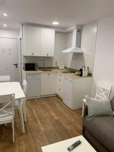 cocina con armarios blancos, mesa y sofá en Apartamentos Lux Carrión, en Carrión de los Condes