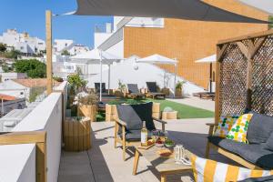 a rooftop patio with chairs and an umbrella at Golden Stay - B&B Experience in Albufeira