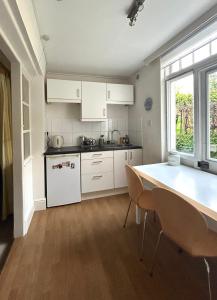a kitchen with white cabinets and a table and chairs at East Finchley N2 apartment close to Muswell Hill & Alexandra Palace with free parking on-site in London