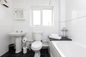 uma casa de banho branca com um WC, uma banheira e um lavatório. em Beautiful House by Station with Private Parking em Cambridge