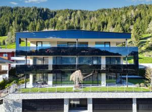 a house with a glass facade with mountains in the background at Timeless Dolomites Apartments in Dobbiaco