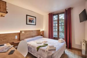 a bedroom with a bed and a table and a window at Cit'H&ocirc;tel Le National in Cluses
