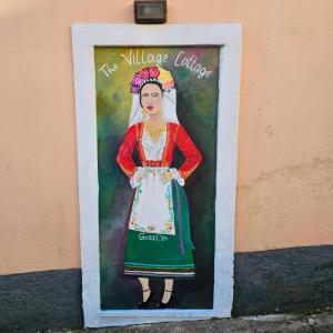 uma pintura de uma mulher ao lado de um edifício em The Village Cottage - Benitses em Benitses