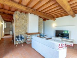 a large living room with a stone wall and wooden ceiling at La Macchia - I Borghi Della Selvaccia in Cennina