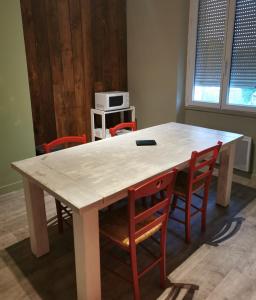 une table blanche avec des chaises et un four micro-ondes sur une étagère dans l'établissement BUREAUX Appartements LESPARRE MEDOC, à Lesparre-Médoc