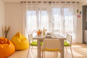 ein Esszimmer mit einem Holztisch und gelben Stühlen in der Unterkunft Villa Piña in Corralejo