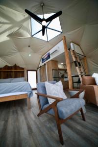 Schlafzimmer mit einem Deckenventilator, einem Stuhl und einem Bett in der Unterkunft Pure Heart Retreat in Cody