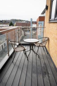 盧頓的住宿－Luxury 2 Bed Apartment in Town Centre - FREE WIFI!!，阳台甲板上的一张桌子和两把椅子