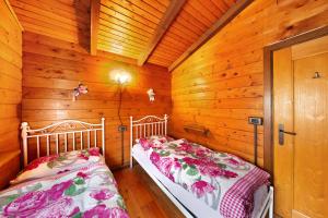two beds in a room with wooden walls at Orserose Chalet 1 La Bilancia in Forno di Zoldo